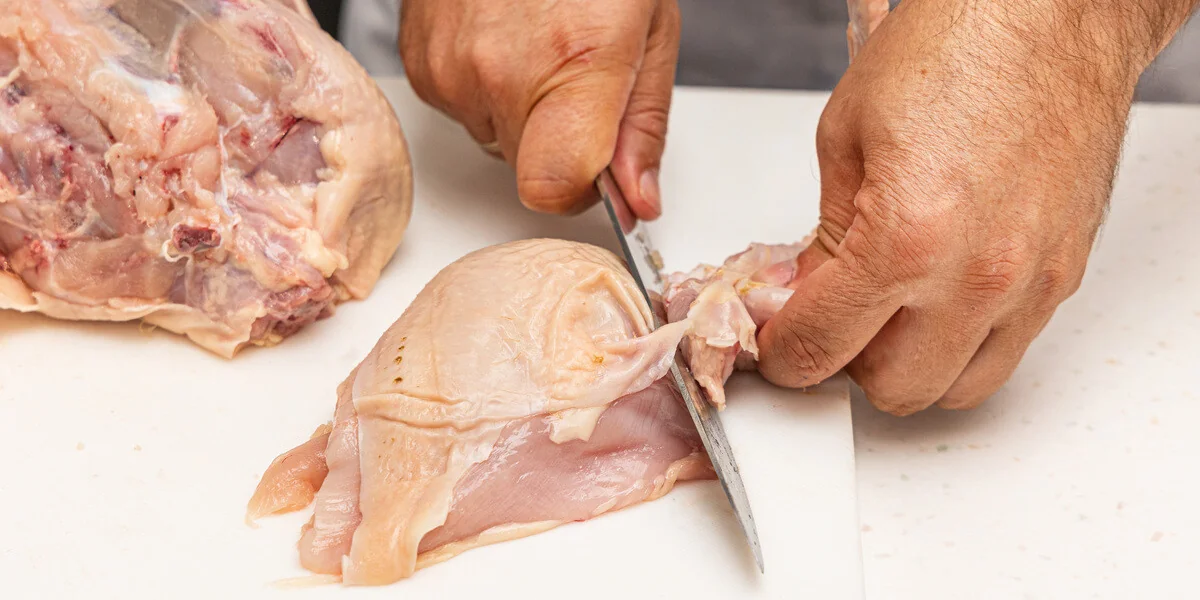 <b>Шаг 3: Отделяем крылья</b><br>Возьмите отделенную грудку. Найдите соединительный сустав между грудкой и крылом. Отведите крыло в сторону, натянув кожу, и аккуратно срежьте его по суставу.