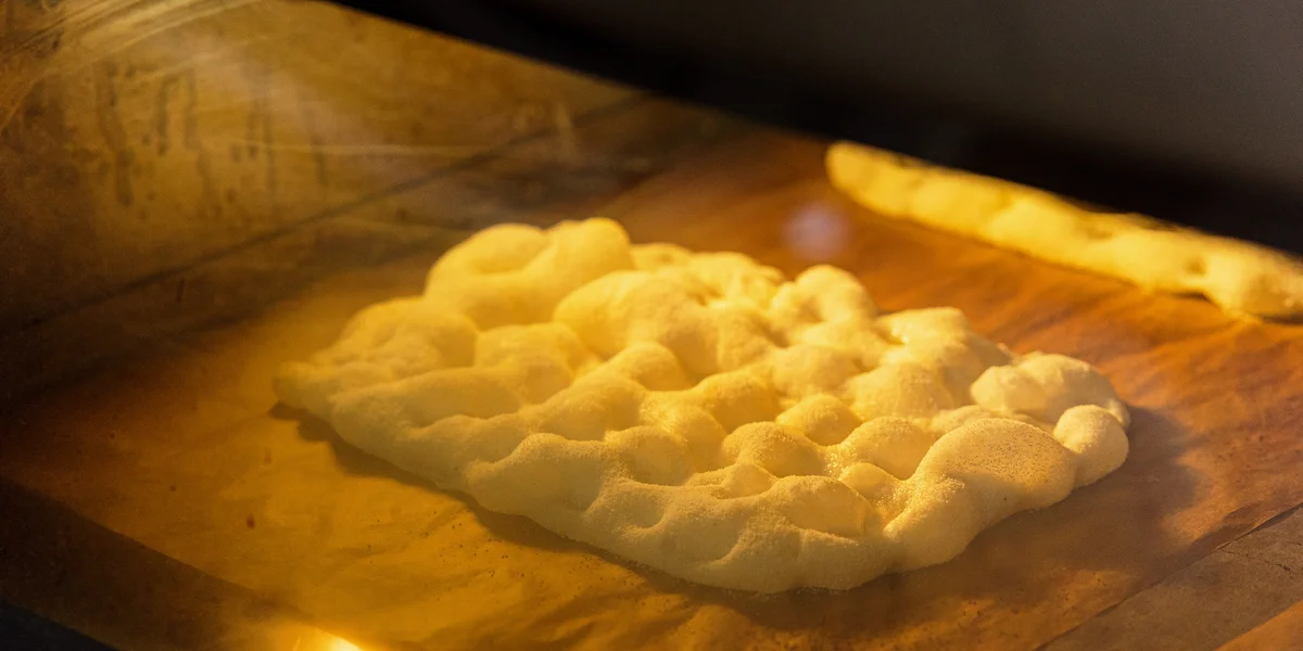 Основу для пиццы достают из печи…