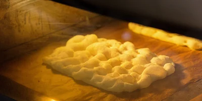 Основу для пиццы достают из печи…