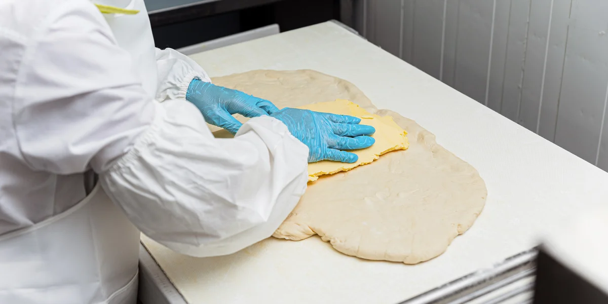 В пласт теста укладывают масло, заворачивают его, а затем прокатывают