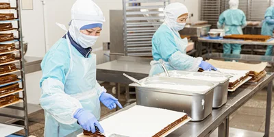 Тесто для этого медовика готовится на водяной бане, где в большом котле все процессы длятся продолжительное время. В жидком виде тесто наносится на листы, выпекается и специально карамелизуется