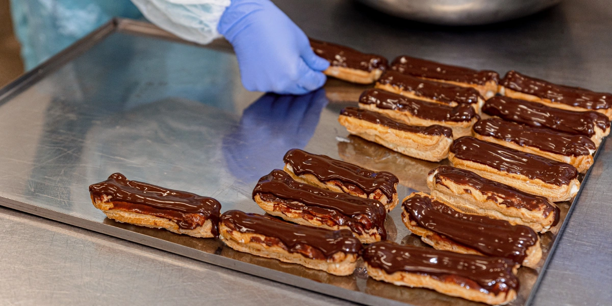 Ванильный эклер украшают ганашем из тёмного шоколада. Сочетание горчинки шоколада и сладости начинки придаёт десерту необычный вкус