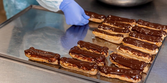 Ванильный эклер украшают ганашем из тёмного шоколада. Сочетание горчинки шоколада и сладости начинки придаёт десерту необычный вкус