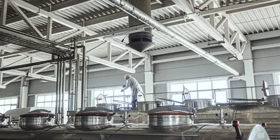 Водитель перемешивает молоко, а лаборант завода отбирает пробы и проводит анализ партии