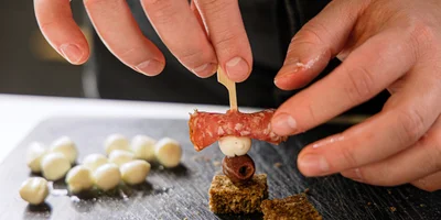 Сверните ломтики колбасы, хлеб нарежьте одинаковыми кусочками. Последовательно наколите на шпажку колбасу, сыр, оливку и хлеб