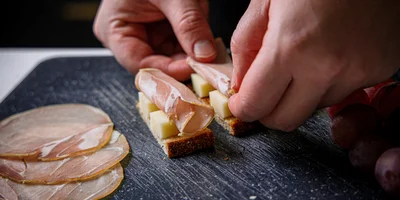 Нарежьте сыр на брусочки, а виноград на половинки