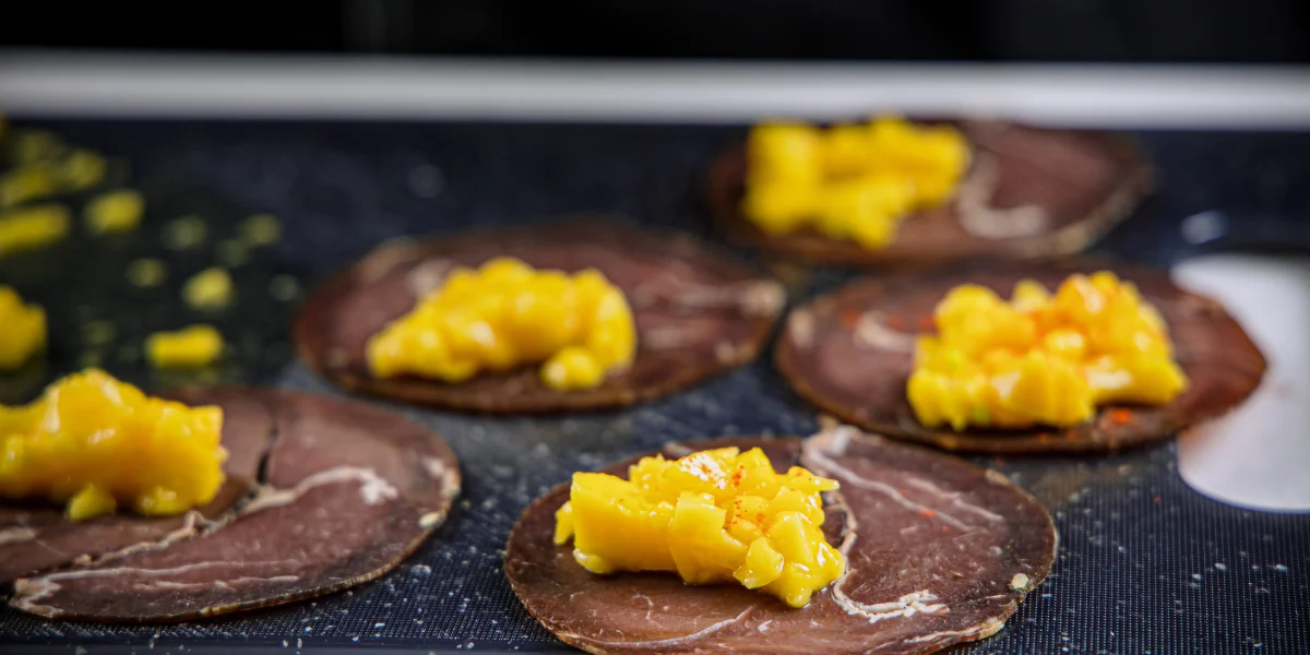 Выложите манго на ломтики говядины и сверните их конвертиками, сверху в качестве украшения присыпьте манго паприкой