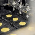 Тесто равномерно дозируют на быстро движущиеся разогретые формы и прессуют круглыми горячими пластинами, чтобы придать ему форму