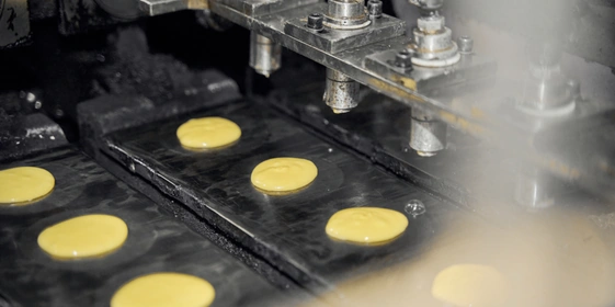 Тесто равномерно дозируют на&nbsp;быстро движущиеся разогретые формы и&nbsp;прессуют круглыми горячими пластинами, чтобы придать ему форму