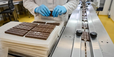 Сотрудники вручную выкладывают шоколадные плитки на&nbsp;упаковочный стол