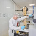 Упаковочные пакеты формируются в подобие тоннеля, в который заходит шоколадка. Затем машина сразу же запаивает упаковку и ножами отрезает её от общей ленты
