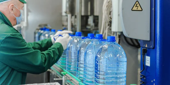 Наполненная водой бутылка поступает по транспортёру на этикетировку