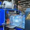 Бутылки с водой поступают в группиратор, который формирует упаковку и подаёт её в термоусадочную печь