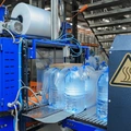 Бутылки с водой поступают в группиратор, который формирует упаковку и подаёт её в термоусадочную печь