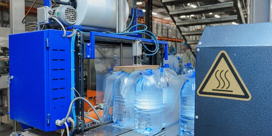 Бутылки с водой поступают в группиратор, который формирует упаковку и подаёт её в термоусадочную печь