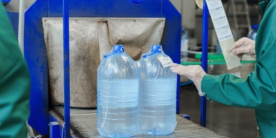 Бутылки с водой поступают в группиратор, который формирует упаковку и подаёт её в термоусадочную печь