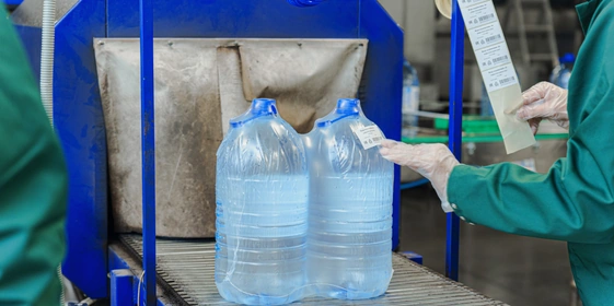 Бутылки с водой поступают в группиратор, который формирует упаковку и подаёт её в термоусадочную печь