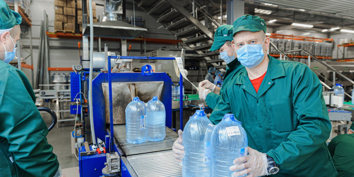 Бутылки с водой поступают в группиратор, который формирует упаковку и подаёт её в термоусадочную печь