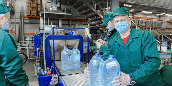 Бутылки с водой поступают в группиратор, который формирует упаковку и подаёт её в термоусадочную печь